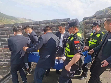 民警與景區(qū)工作人員將患病游客抬下長城。
