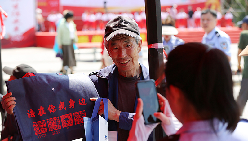 頭題圖,法治文藝節(jié)目展演活動(dòng)現(xiàn)場(chǎng),司法局工作人員發(fā)放原創(chuàng)普法購(gòu)物袋。