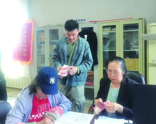 發(fā)放現(xiàn)場，付菊（右一）逐筆核對勞務(wù)費（受訪單位供圖）